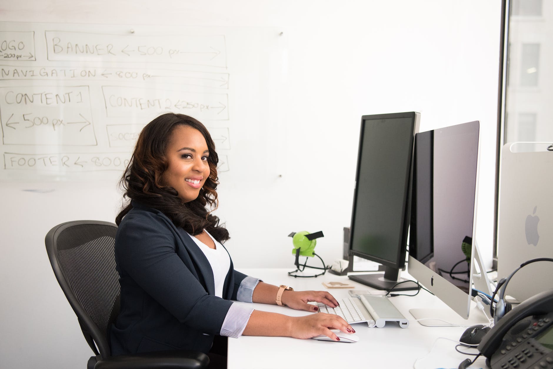 woman in professional wear seated in front of monitor