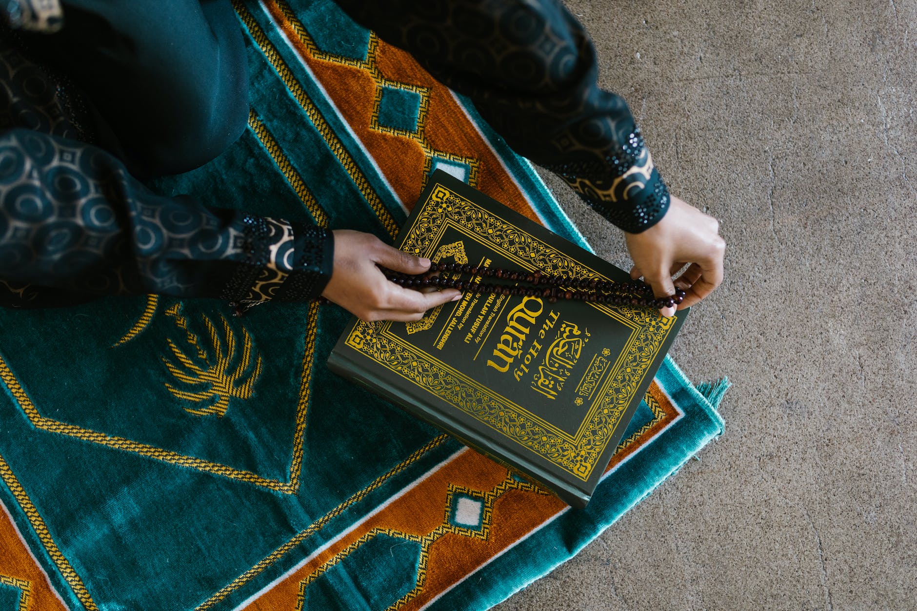 hands of a person holding a prayer beads on a book